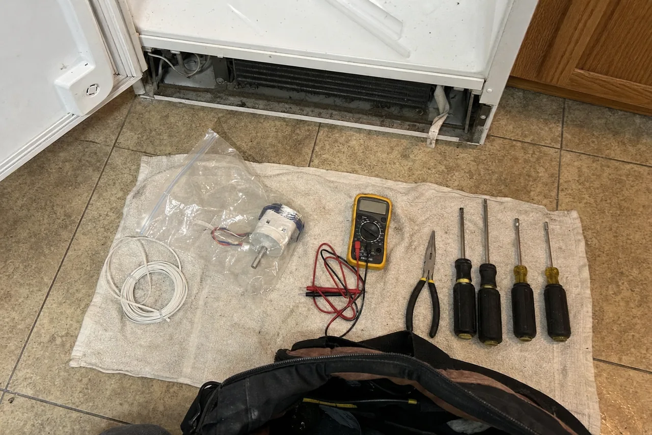 Mirrored overhead of the same tool lay-out, the bagged evaporator fan motor and a coil of thermistor wire nearest the camera.